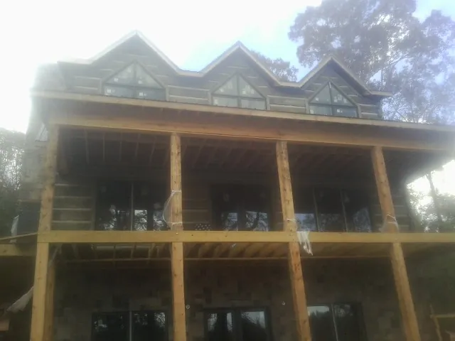 Dormers and porch framing on a large log home under construction — Roof Coating work by our crew in Sharpes