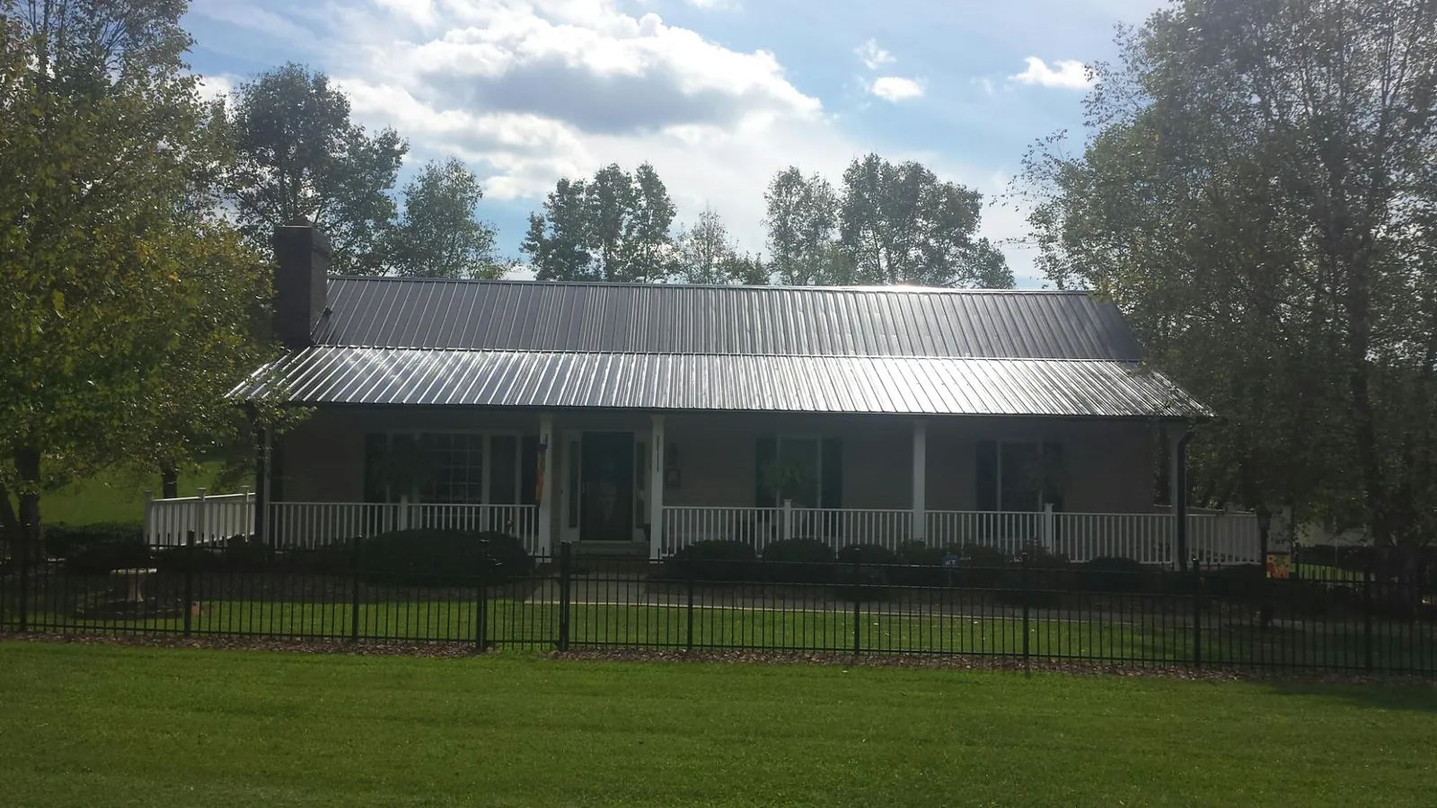Gray metal roof on a brick ranch with a full width front porch — Gutter Guard Installation work by our crew in Sharpes