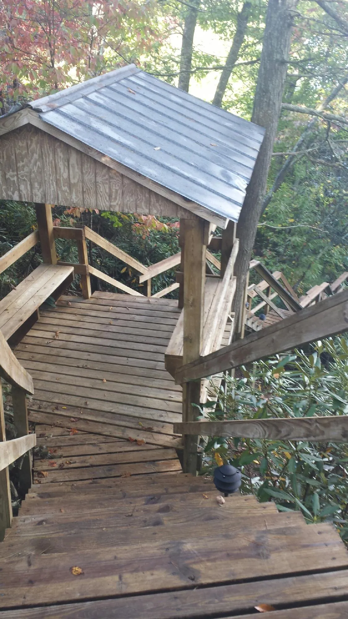 Metal roofed shelter over wooden steps on a wooded walkway — Skylight Repair & Installation work by our crew in Sharpes